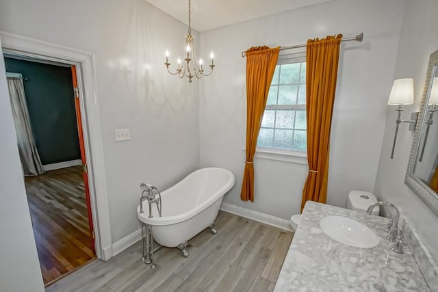 bathroom with hardwood / wood-style floors, vanity, a tub, and a notable chandelier