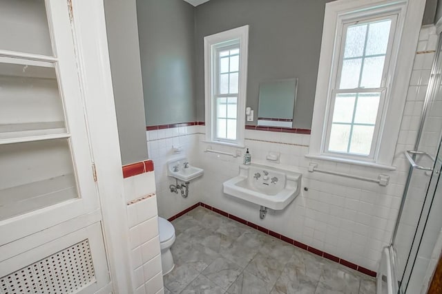 bathroom with plenty of natural light, toilet, and tile walls