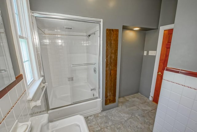 bathroom with enclosed tub / shower combo and tile walls