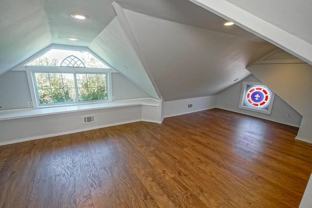 additional living space with hardwood / wood-style flooring and vaulted ceiling