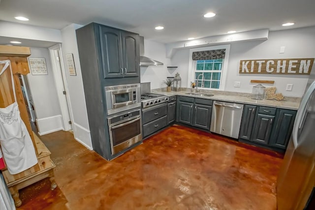 kitchen with gray cabinetry, sink, stainless steel appliances, wall chimney range hood, and light stone counters