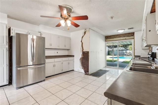 kitchen featuring sink, white cabinetry, a textured ceiling, stainless steel refrigerator, and ceiling fan