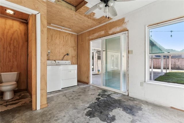 clothes washing area with ceiling fan, washing machine and dryer, and wooden walls