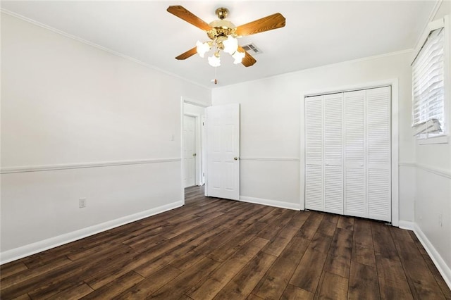 unfurnished bedroom with crown molding, dark hardwood / wood-style floors, a closet, and ceiling fan