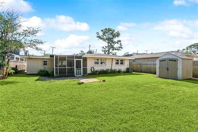 rear view of property featuring a yard, a sunroom, and a storage unit