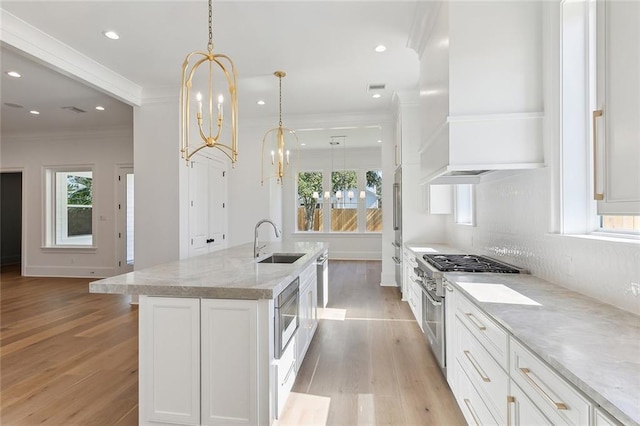 kitchen with a notable chandelier, white cabinetry, sink, and hanging light fixtures