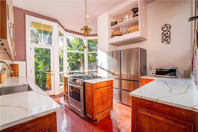 kitchen featuring appliances with stainless steel finishes, a healthy amount of sunlight, sink, and light stone countertops