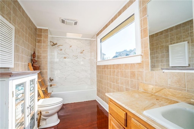 full bathroom with toilet, tiled shower / bath combo, and tile walls