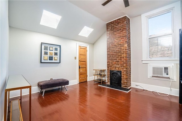 interior space featuring vaulted ceiling with skylight, cooling unit, a fireplace, and hardwood / wood-style floors