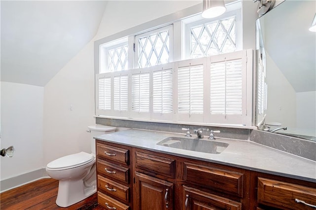 bathroom featuring vanity, hardwood / wood-style floors, vaulted ceiling, and toilet