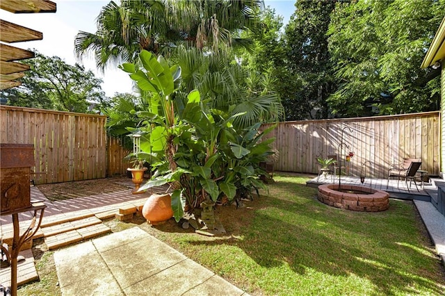 view of yard featuring a wooden deck, a patio, and a fire pit