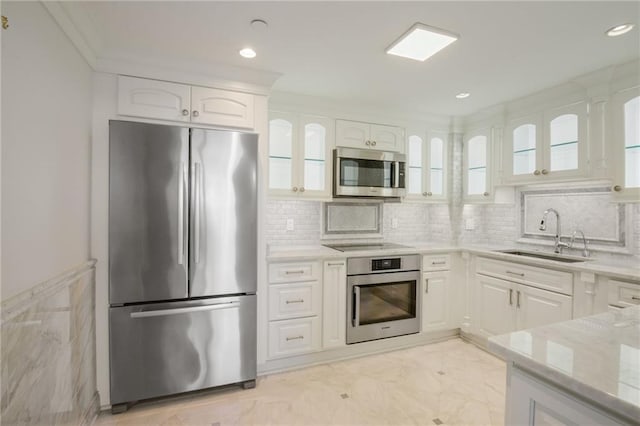 kitchen with appliances with stainless steel finishes, white cabinets, tasteful backsplash, and sink