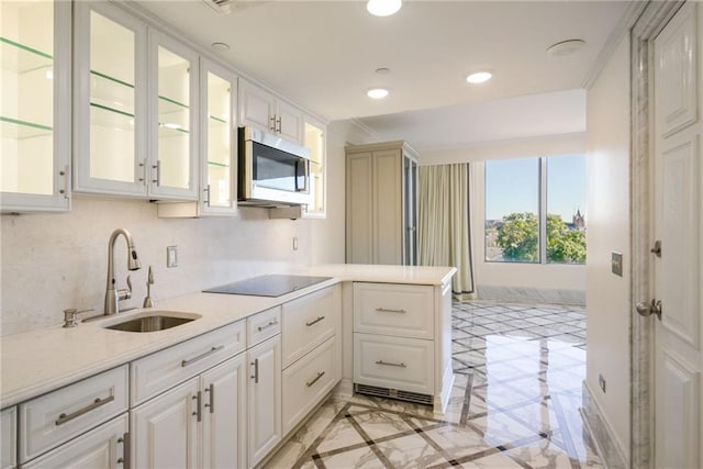 kitchen featuring kitchen peninsula, white cabinets, light stone counters, black electric stovetop, and sink