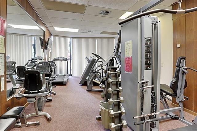 gym with a drop ceiling, wooden walls, and carpet flooring