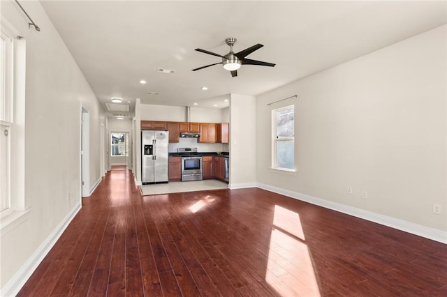 unfurnished living room with plenty of natural light, wood finished floors, and baseboards