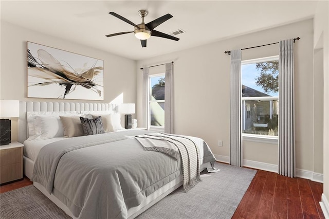 bedroom featuring baseboards, ceiling fan, visible vents, and wood finished floors