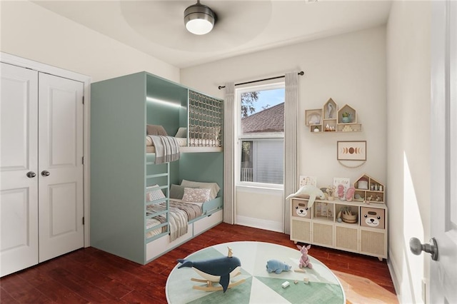 bedroom with a closet, baseboards, wood finished floors, and a ceiling fan