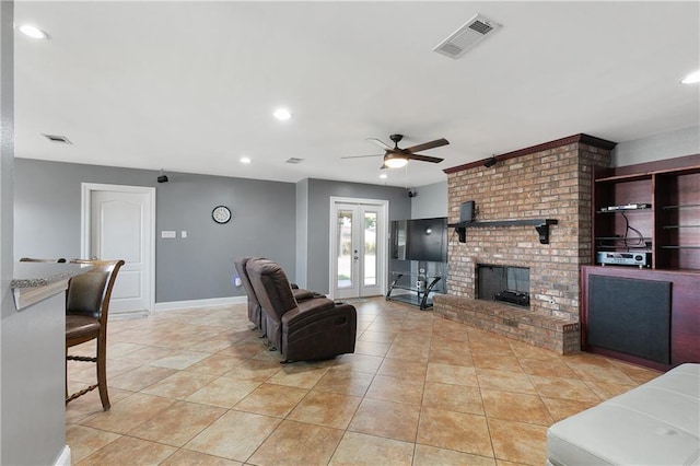 living room with french doors, ceiling fan, light tile patterned flooring, and a brick fireplace