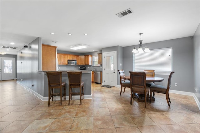 kitchen featuring a breakfast bar area, kitchen peninsula, stainless steel appliances, light tile patterned flooring, and a chandelier