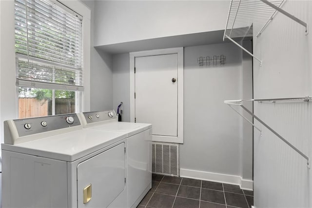 laundry area with dark tile patterned floors and washer and clothes dryer