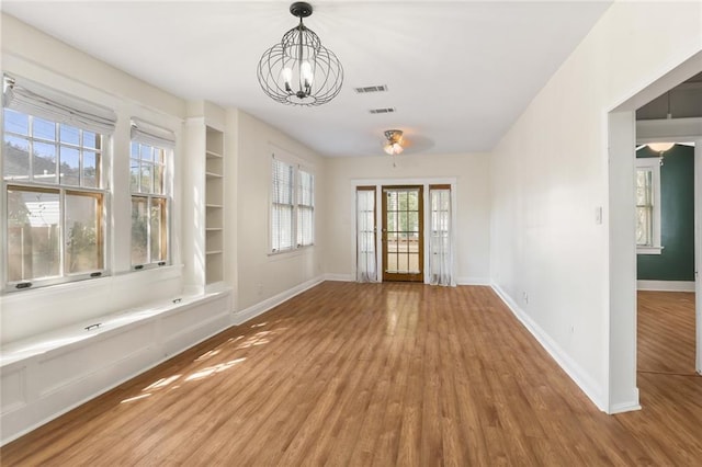 unfurnished dining area with wood-type flooring and ceiling fan with notable chandelier