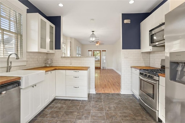 kitchen with white cabinets, appliances with stainless steel finishes, and wooden counters