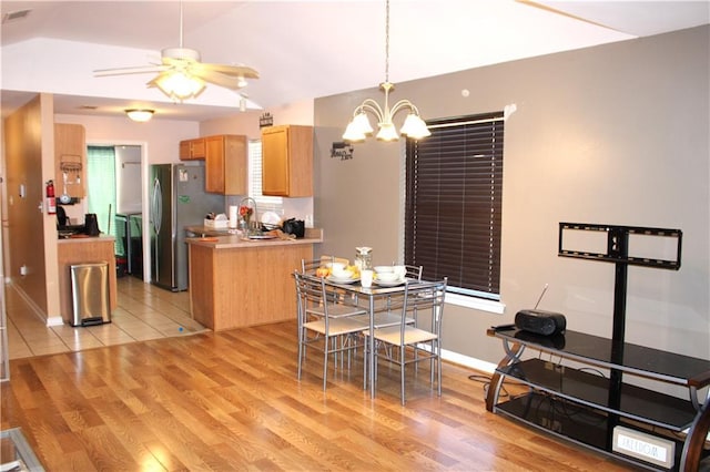 dining room featuring vaulted ceiling, ceiling fan with notable chandelier, and light hardwood / wood-style floors