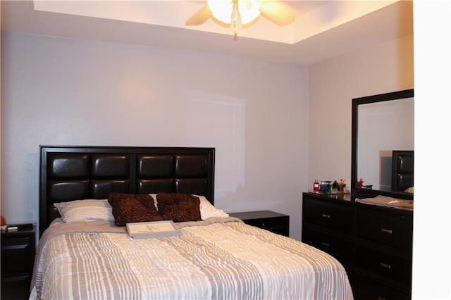 bedroom with ceiling fan and a raised ceiling