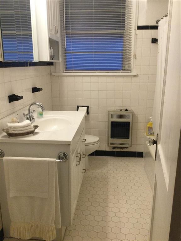 bathroom featuring toilet, tile walls, heating unit, vanity, and tile patterned flooring