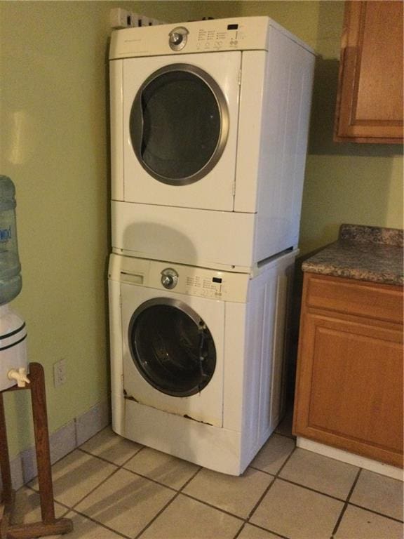 laundry area featuring light tile patterned floors and stacked washing maching and dryer