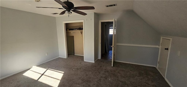 unfurnished bedroom featuring lofted ceiling, a closet, dark carpet, and ceiling fan