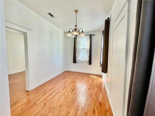 interior space with a chandelier, a barn door, and light hardwood / wood-style floors