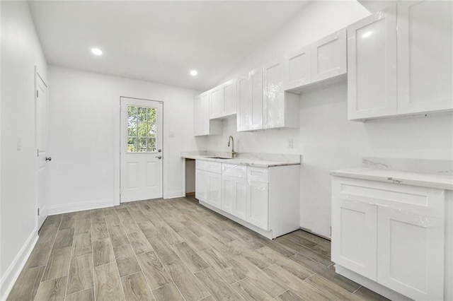 kitchen with white cabinetry, light hardwood / wood-style floors, and sink