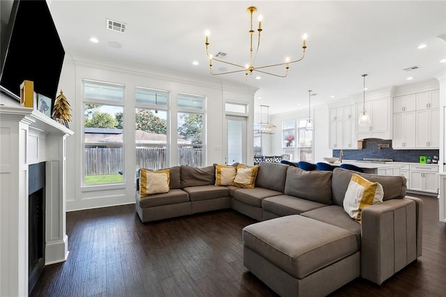 living room with crown molding, dark hardwood / wood-style floors, and a chandelier