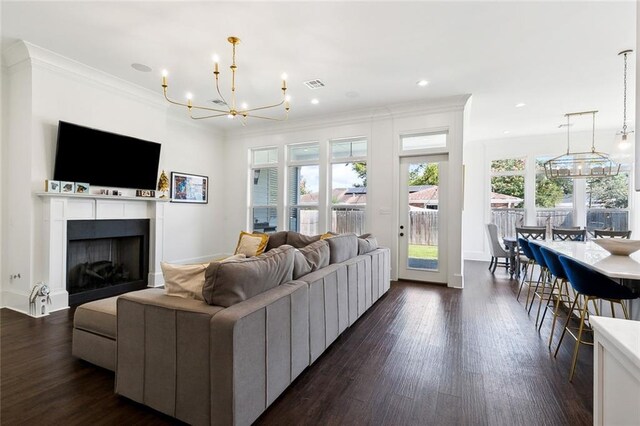 living room with dark wood-type flooring, crown molding, and an inviting chandelier