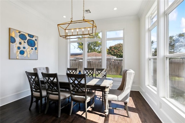 dining area with a notable chandelier, ornamental molding, and dark hardwood / wood-style floors