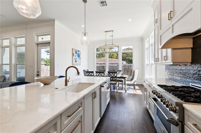 kitchen with sink, white cabinetry, stainless steel appliances, custom range hood, and decorative light fixtures