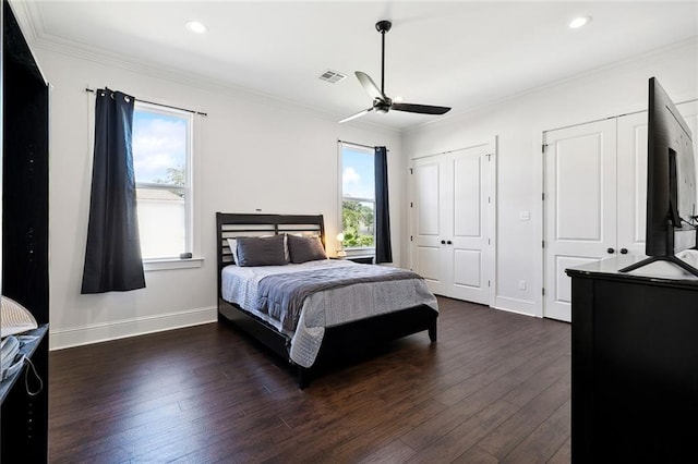 bedroom featuring multiple closets, ceiling fan, crown molding, and dark wood-type flooring