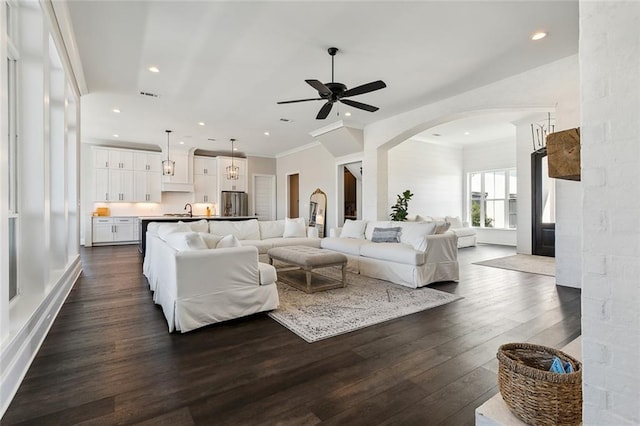 living room featuring ceiling fan, crown molding, sink, and dark hardwood / wood-style flooring