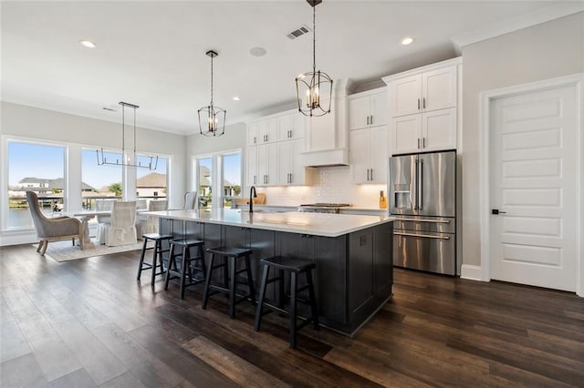 kitchen with high quality fridge, a large island, decorative light fixtures, and white cabinets