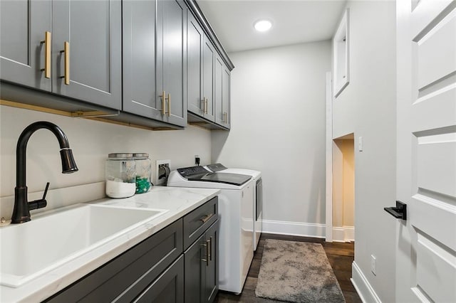 clothes washing area featuring cabinets, dark hardwood / wood-style floors, sink, and washing machine and clothes dryer