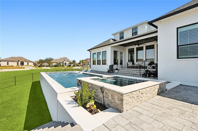 view of swimming pool with a patio, a lawn, an in ground hot tub, pool water feature, and ceiling fan