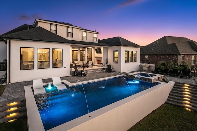 back house at dusk featuring a swimming pool with hot tub, a patio, and pool water feature