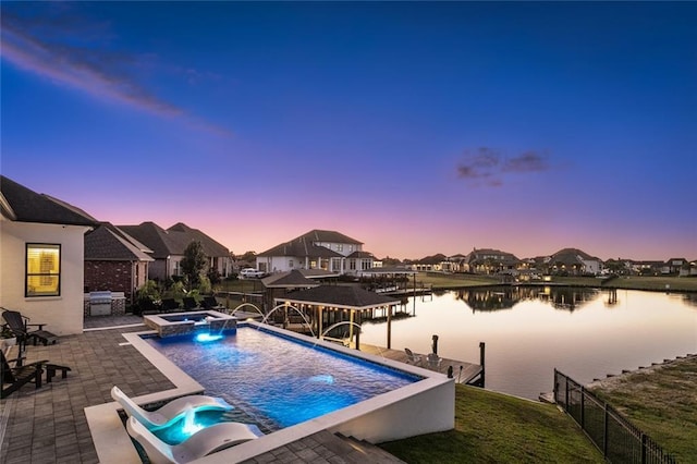 pool at dusk featuring a water view, an in ground hot tub, pool water feature, and a boat dock