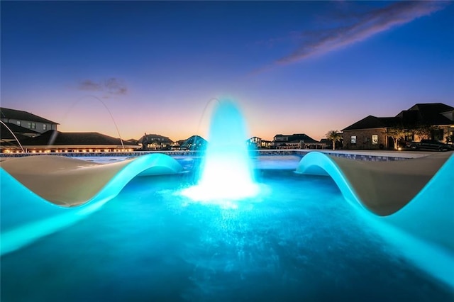 pool at dusk featuring a water slide