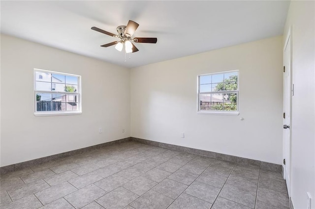 spare room featuring a wealth of natural light, light tile patterned flooring, and ceiling fan