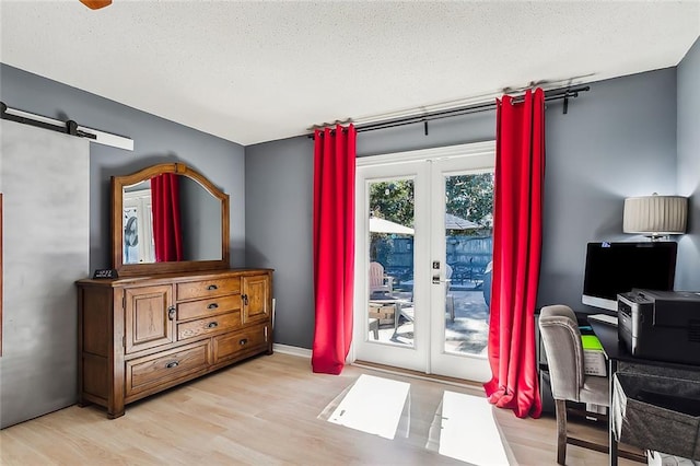 entryway featuring french doors, a barn door, a textured ceiling, and light wood-type flooring