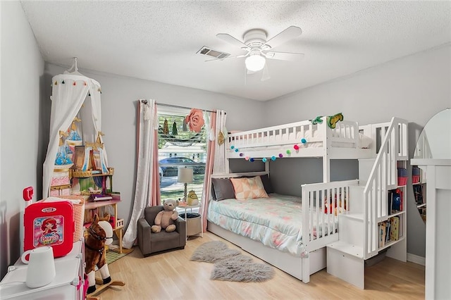 bedroom featuring ceiling fan, a textured ceiling, and light hardwood / wood-style flooring