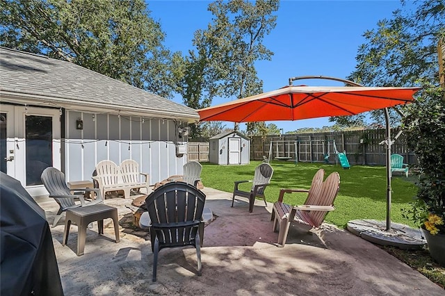 view of patio with a shed, a playground, and a fire pit