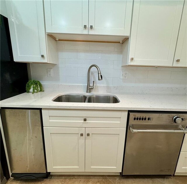 kitchen with light stone counters, backsplash, white cabinetry, a sink, and dishwasher